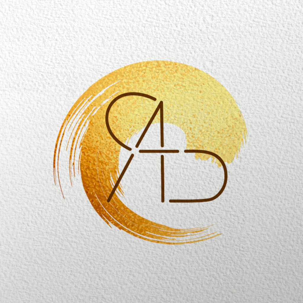 Cette image représente un logo sur un fond papier texturé. Le logo représente un coup de pinceau circulaire doré. Par dessus, il-y-a le monogramme de l'entreprise qui est tracé en marron et qui représente les lettre A,D et C entremêlées. 